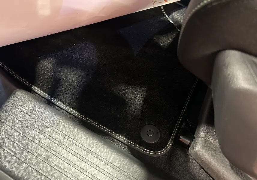 Gros plan sur le tapis de sol noir avec surpiqûres blanches côté conducteur du Peugeot 3008 gris Artense 2025.