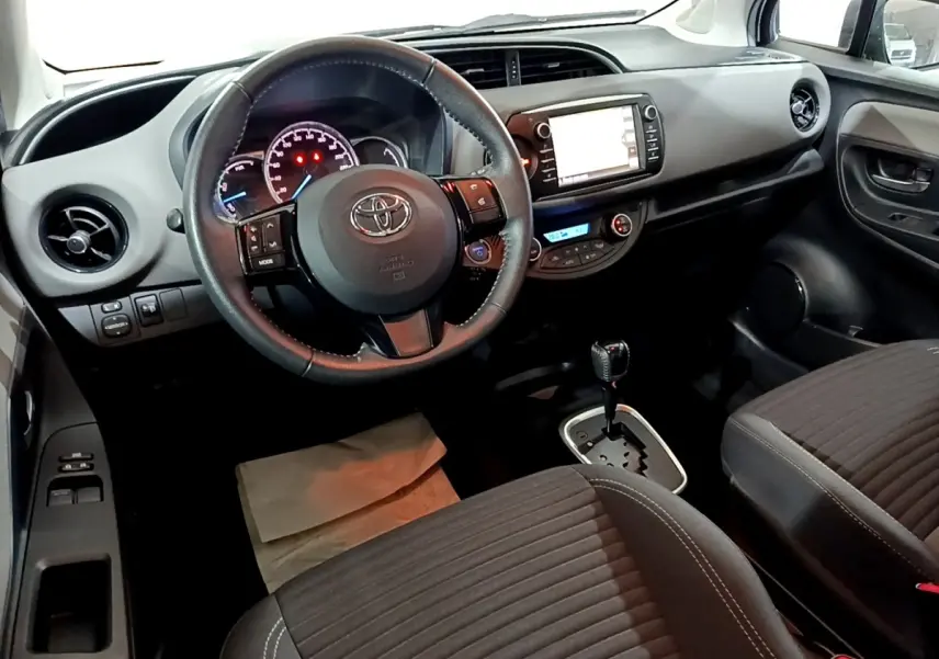 Vue intérieure avant de la Toyota Yaris 1.5 Hybride 2020, volant cuir alu multifonctions et écran tactile central visible.