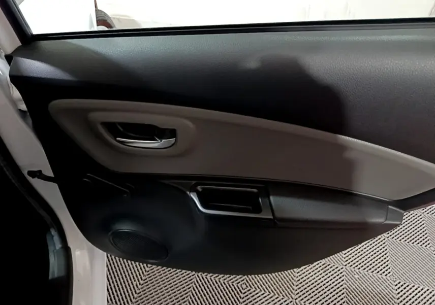 Vue intérieure de la porte avant gauche blanche d'une Toyota Yaris 1.5 Hybride 2020 avec poignée chrome et haut-parleur intégré.