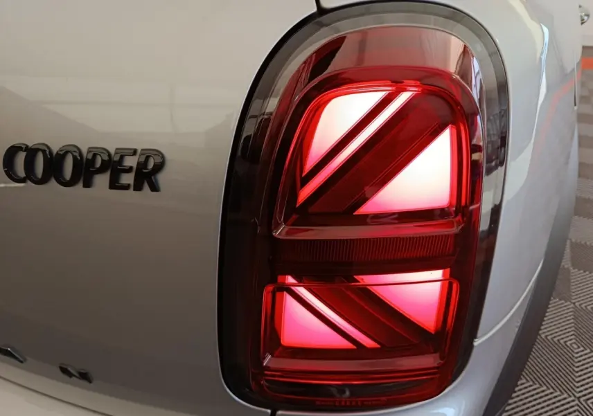 Gros plan sur le feu arrière droit rouge et le logo Cooper sur la carrosserie gris foncé du MINI Countryman 2023.