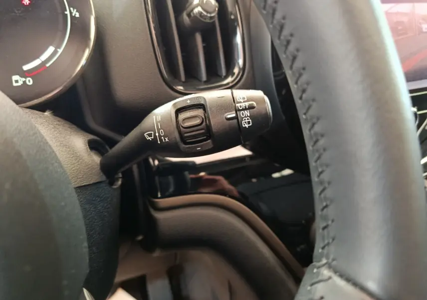 Gros plan sur la commande d’essuie-glace à gauche du volant cuir dans l’habitacle noir du MINI Countryman gris foncé 2023.