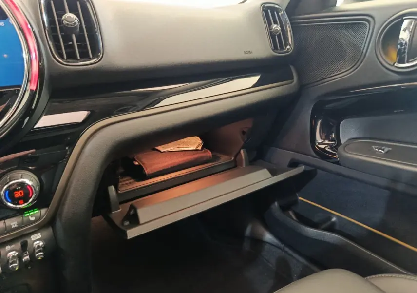 Intérieur du MINI Countryman Cooper 2023, vue côté passager sur boîte à gants ouverte avec tableau de bord noir brillant.