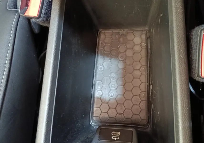 Vue rapprochée de la console centrale noire avec zone de recharge à induction et port USB-C du MINI Countryman gris foncé.