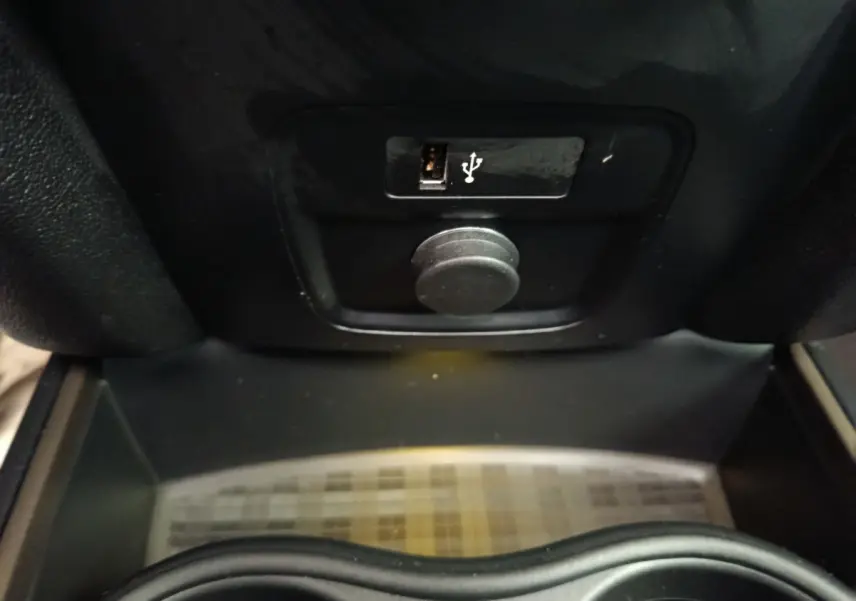 Gros plan sur la prise USB et la prise 12V dans le compartiment central d’un MINI Countryman gris foncé.