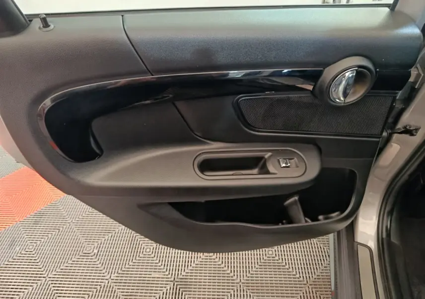 Vue rapprochée de la porte avant droite noire intérieure du MINI Countryman gris foncé 2023 avec poignée chromée.