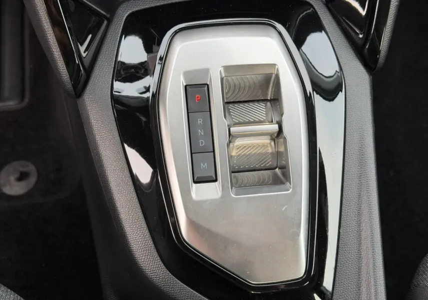 Vue rapprochée de la commande de boîte automatique noire et argentée de la Peugeot 208 blanche Okénite.