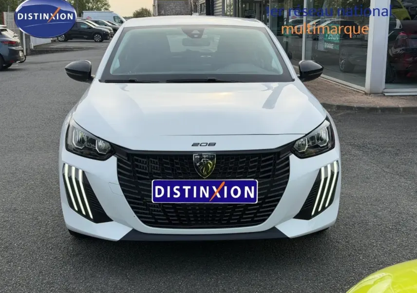 Vue avant d'une Peugeot 208 blanche Okénite avec calandre noire et feux LED verticaux distinctifs allumés.