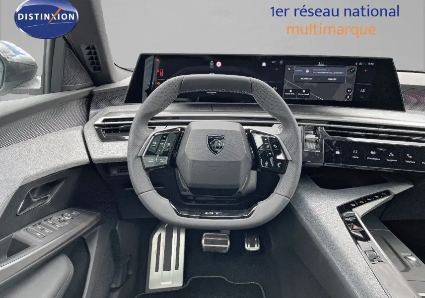 Vue intérieure centrée sur le volant GT du Peugeot 5008 Hybrid 2025 avec tableau de bord numérique et finitions grises.