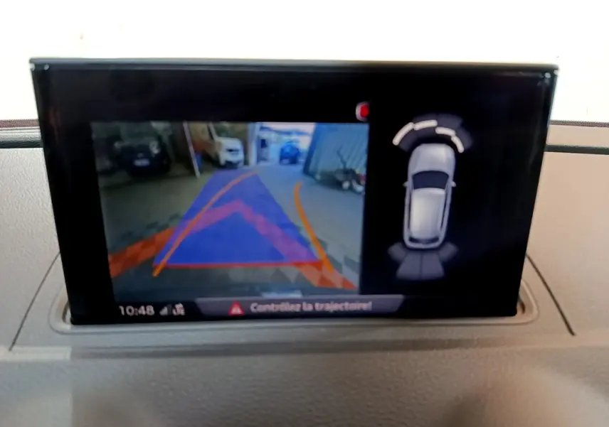 Écran intérieur affichant la caméra de recul et les capteurs de stationnement de l'Audi A3 gris foncé, vue du tableau de bord.