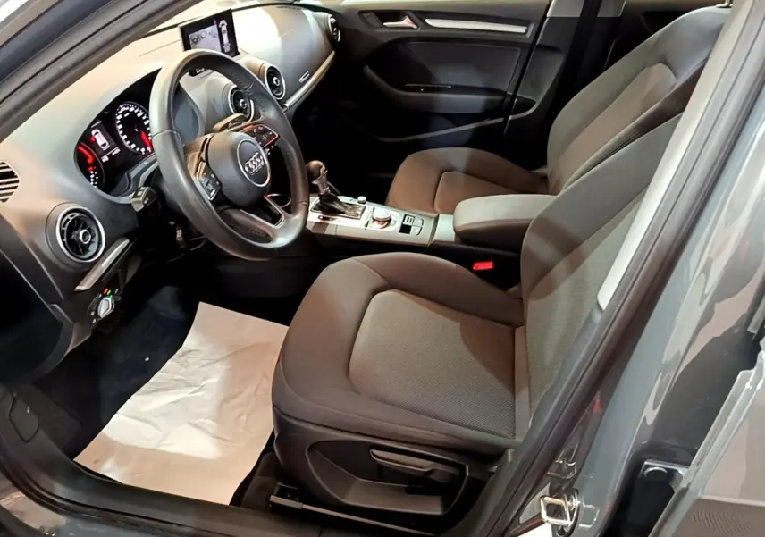 Vue intérieure côté conducteur de l'Audi A3 30 TDI 2019 gris foncé, volant cuir multifonctions et tableau de bord digital.