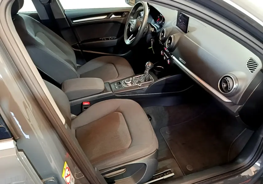 Vue intérieure côté conducteur de l'Audi A3 30 TDI 2019 gris foncé, avec volant cuir multifonctions et tableau de bord digital.