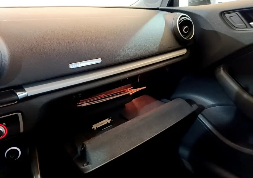 Intérieur de l'Audi A3 30 TDI 2019, vue côté passager sur la boîte à gants ouverte et la planche de bord noire.