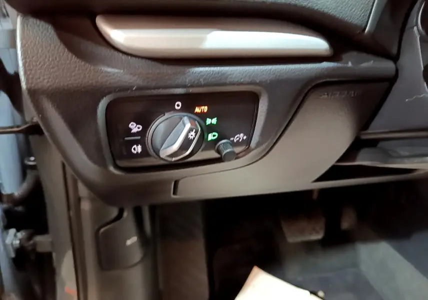 Gros plan sur le panneau de commande des phares à gauche du volant dans l'Audi A3 gris foncé 30 TDI 2019.