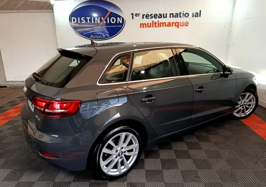 Audi A3 30 TDI gris foncé vue 3/4 arrière droit en intérieur avec jantes alliage et feux arrière allumés.
