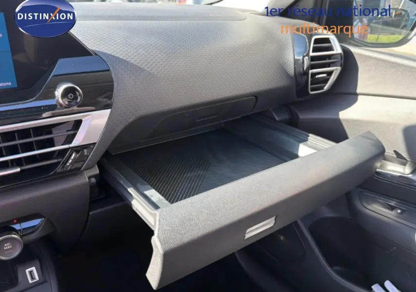 Vue intérieure côté passager du tableau de bord de la Citroën C4 X 2023 avec boîte à gants ouverte et finition noire.