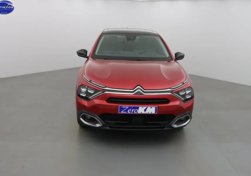 Vue frontale d'une Citroën C4 X rouge Elixir métal avec calandre chromée et feux LED distinctifs allumés.