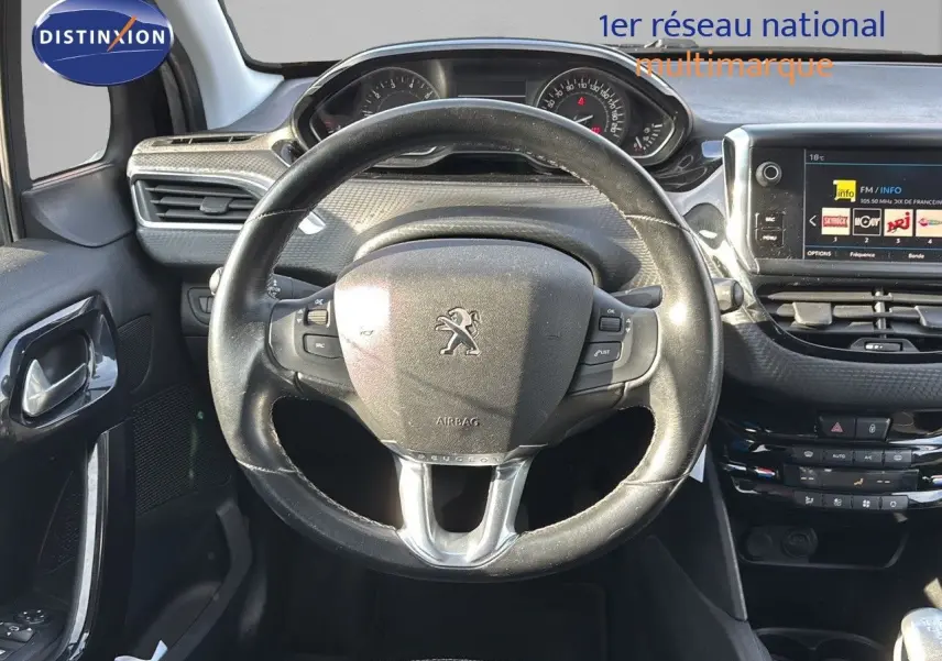 Vue intérieure centrée sur le volant Peugeot 208 1.2 PureTech noir, avec tableau de bord et écran tactile visibles.