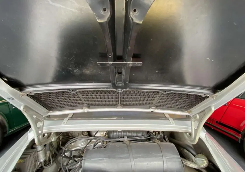 Moteur visible sous le capot ouvert d'une Porsche 911 3.0 SC gris métallisé, vue arrière rapprochée.