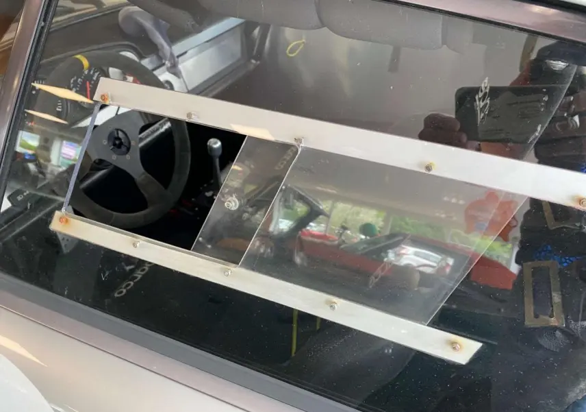 Vue latérale gauche de la Porsche 911 3.0 SC gris métallisé avec vitre latérale en Lexan et intérieur course Sparco visible