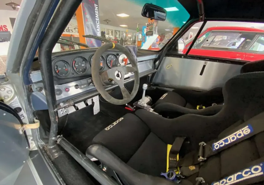 Intérieur côté conducteur d'une Porsche 911 3.0 SC gris métallisé avec baquets Sparco et arceau de sécurité.