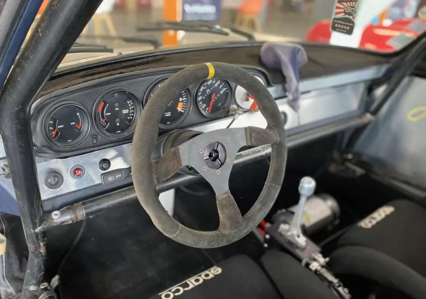 Intérieur de Porsche 911 3.0 SC 1980 vu côté conducteur, volant Sparco, arceau tubulaire et baquets course noirs.