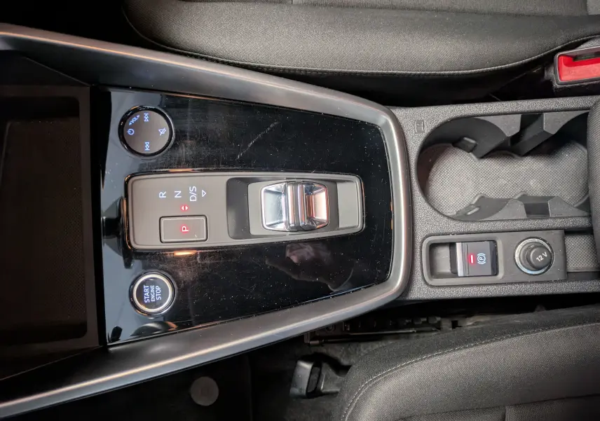 Vue plongeante sur la console centrale noire brillante de l'Audi A3 Sportback 35 TDI avec levier de vitesses automatique et bouton start/stop.