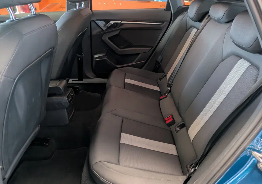 Vue intérieure côté droit des sièges arrière noirs avec bandes grises de l'Audi A3 Sportback bleu Atollblau Metallic 2021.