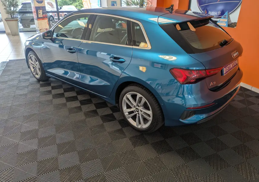 Audi A3 Sportback bleu Atollblau en vue 3/4 arrière droit, soulignant ses lignes dynamiques et ses jantes alliage.