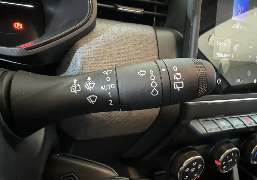 Gros plan sur la commande d'essuie-glace côté gauche du tableau de bord gris clair de la Renault Clio 2025 Evolution Blue dCi 100.