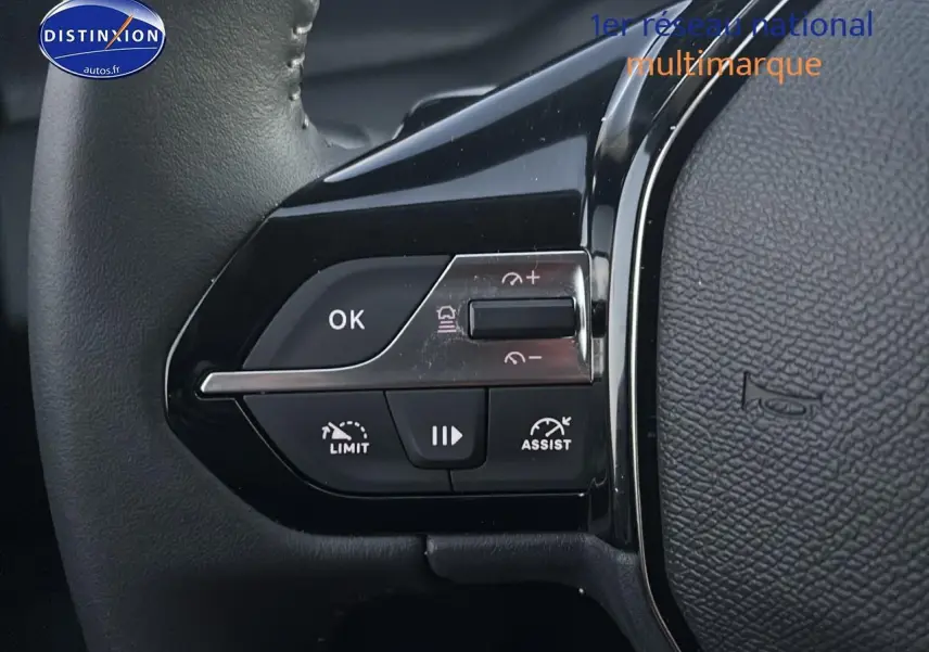 Gros plan sur les commandes de régulateur de vitesse au volant noir de la Peugeot 308 gris artense 2025.