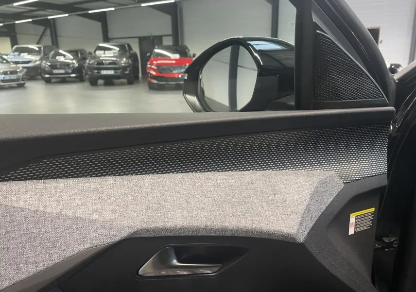Vue intérieure côté gauche de la porte avant d’un Peugeot 3008 noir métallisé, avec tissu gris et inserts noirs laqués.