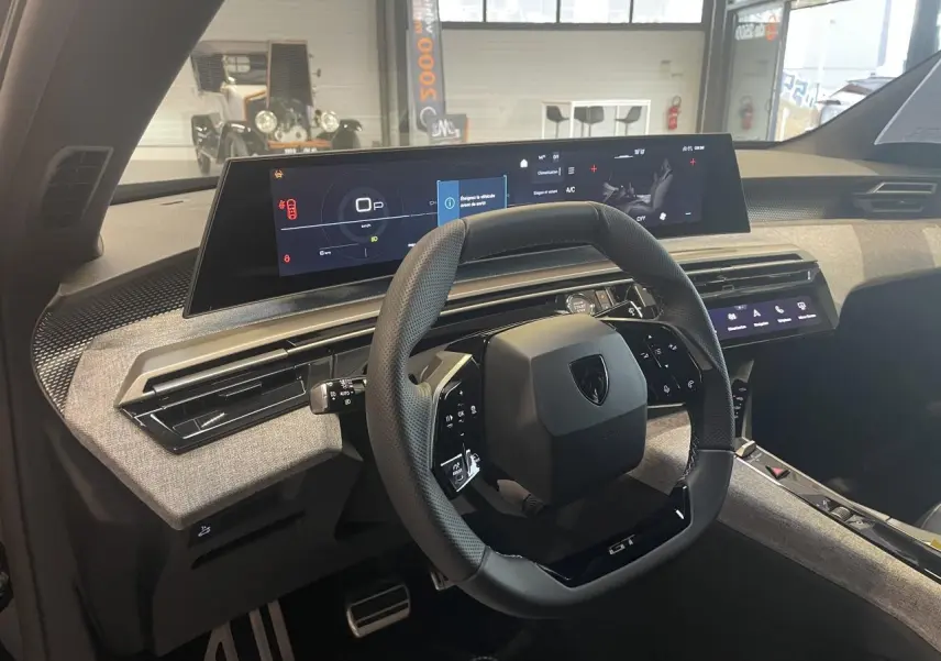 Vue intérieure du poste de conduite du Peugeot 3008 GT 2025, volant compact noir et tableau de bord numérique panoramique.
