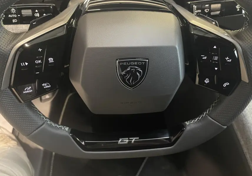 Vue rapprochée du volant noir perforé Peugeot 3008 GT avec commandes intégrées et logo central.