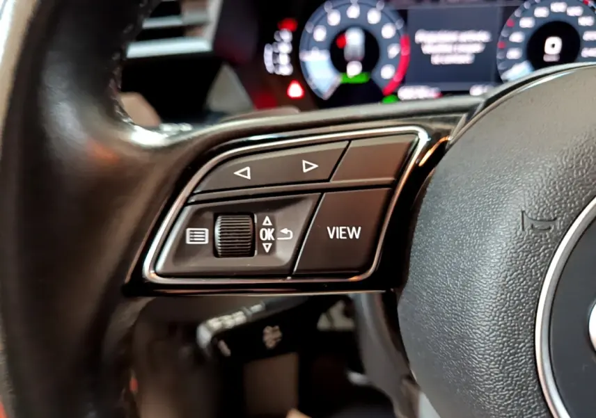 Gros plan sur le côté gauche du volant cuir noir de l’Audi A3 35 TFSI 2021 avec commandes multifonctions visibles.