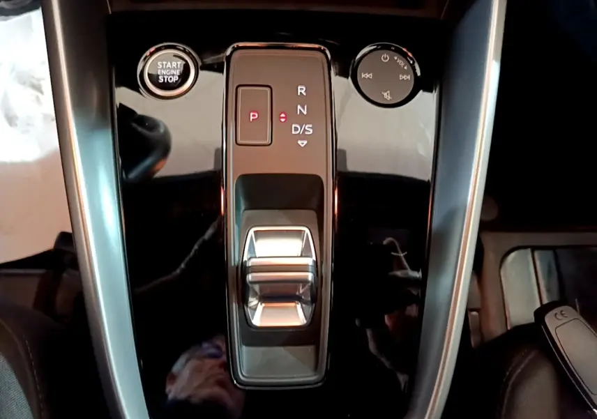 Vue plongeante sur la console centrale noire brillante de l'Audi A3 35 TFSI avec sélecteur de boîte auto et bouton start/stop.