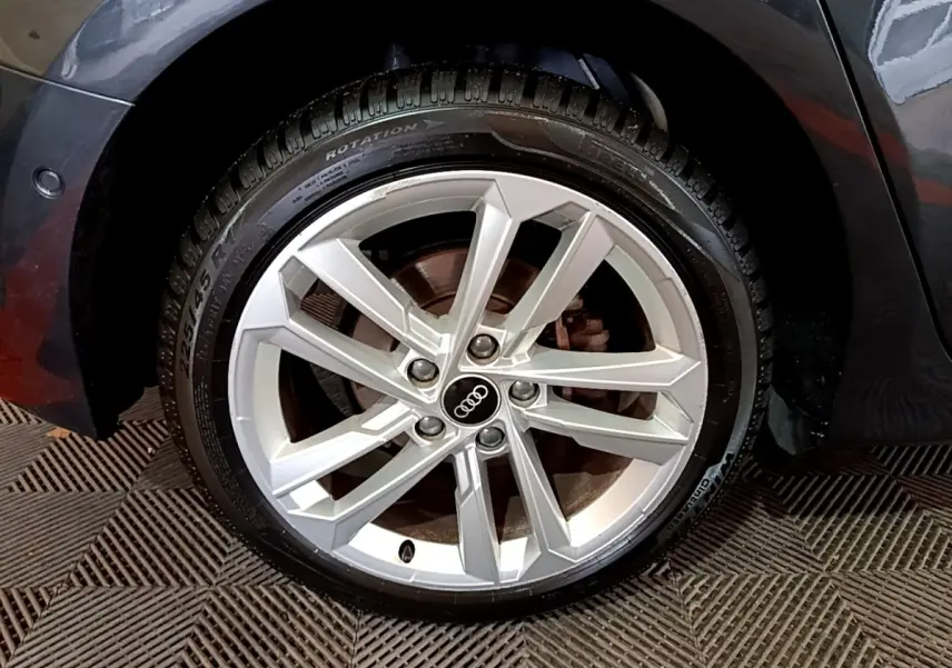 Gros plan sur la roue avant droite d’une Audi A3 gris foncé, mettant en valeur la jante en alliage à design moderne.