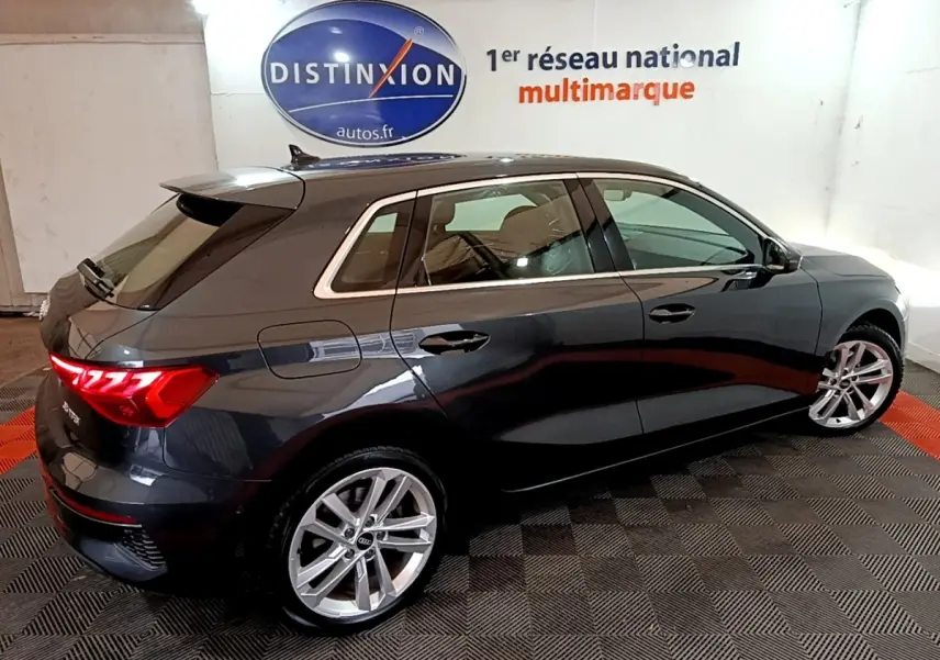 Audi A3 35 TFSI gris foncé vue 3/4 arrière droit, jantes alliage et feux arrière LED allumés.