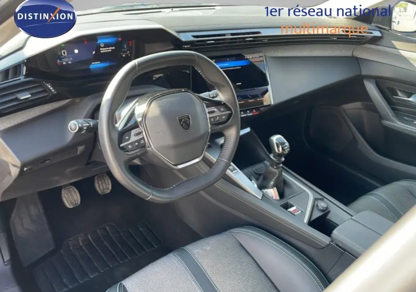 Vue intérieure côté conducteur de la Peugeot 308 1.2 PureTech 130ch Allure 2024, volant cuir et boîte manuelle.