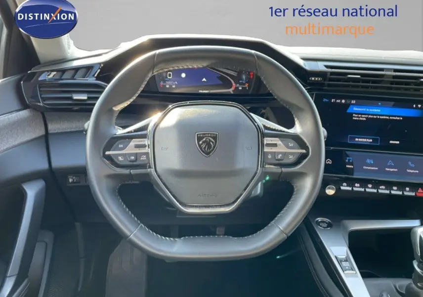 Vue intérieure centrée sur le volant cuir noir de la Peugeot 308 2024 avec tableau de bord digital et écran tactile.