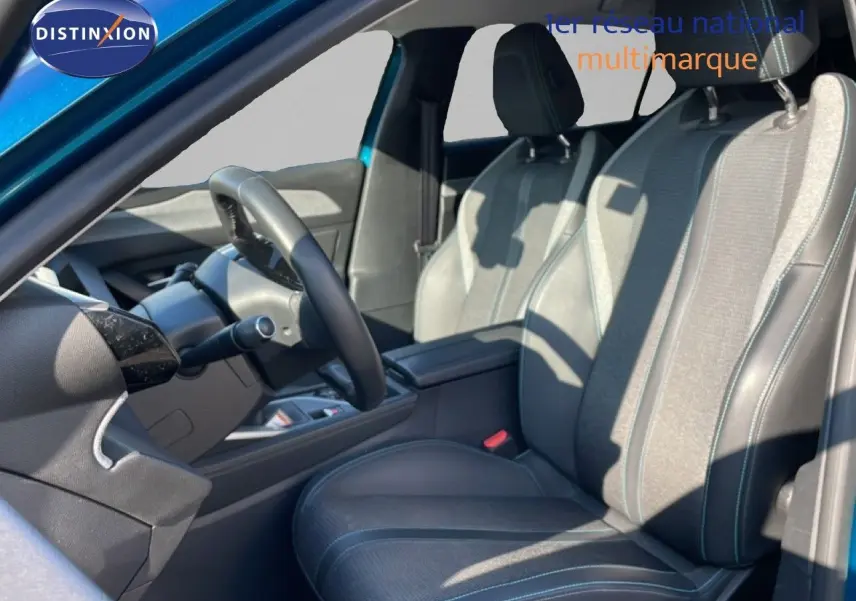 Vue intérieure côté conducteur de la Peugeot 308 2024 bleu obsession, sièges tissu et cuir gris noir avec surpiqûres bleues.