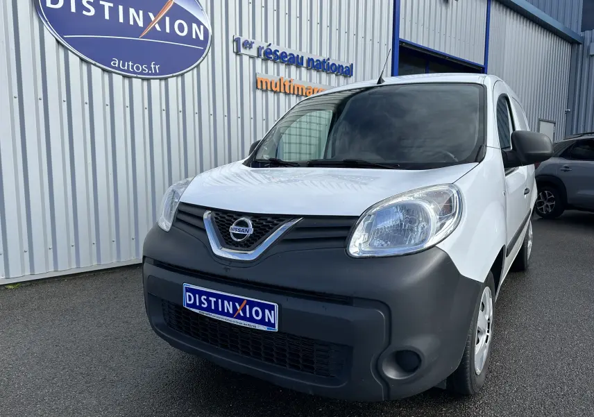 Nissan NV250 blanc en 3/4 avant droit, avec pare-chocs noir mat et logo Nissan visible sur la calandre.