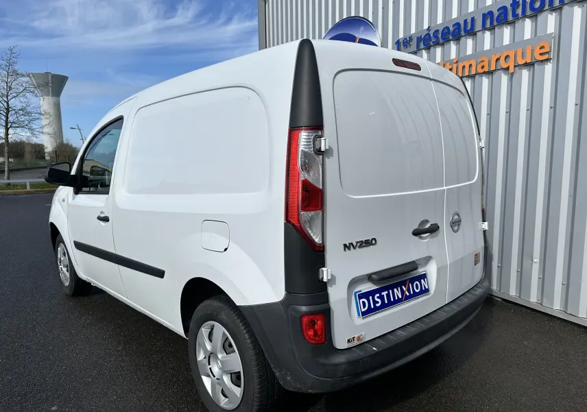Vue 3/4 arrière droite d'un utilitaire Nissan NV250 blanc de 2020 avec logo et plaque Distinxion visible.
