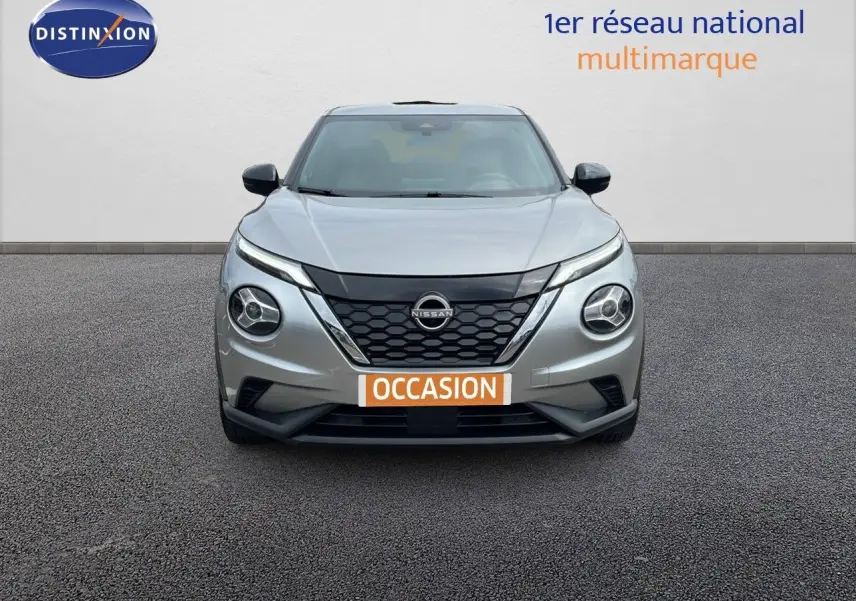 Vue frontale d'un Nissan Juke Hybrid gris perle métal avec calandre noire et phares ronds distinctifs.
