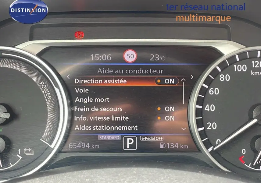 Tableau de bord numérique du Nissan Juke Hybrid 2023 affichant les aides à la conduite et la vitesse limitée à 50 km/h.