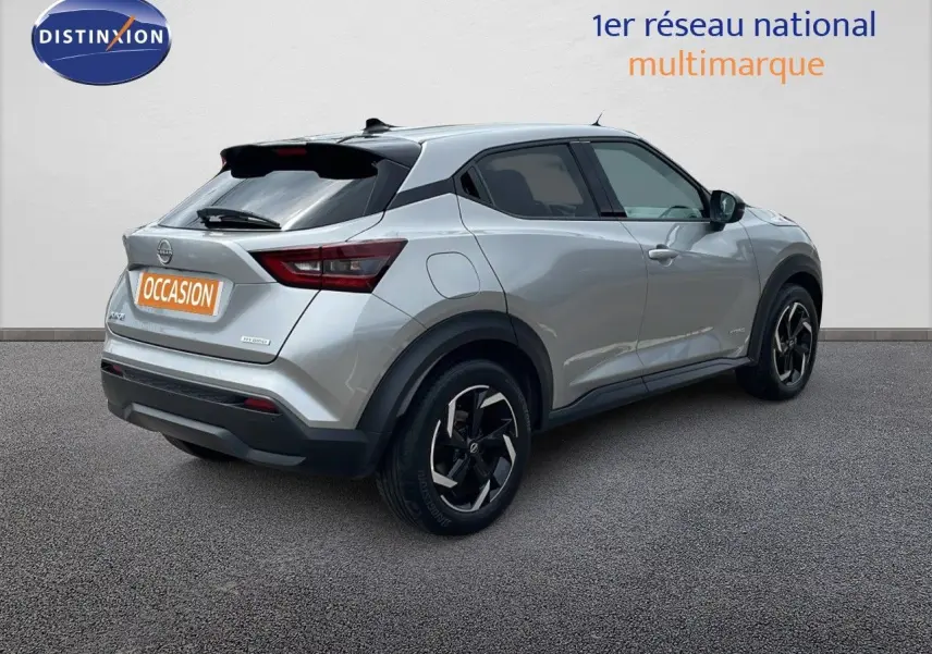 Vue 3/4 arrière droite d'un Nissan Juke hybride gris perle métal avec jantes noires et toit noir contrasté.