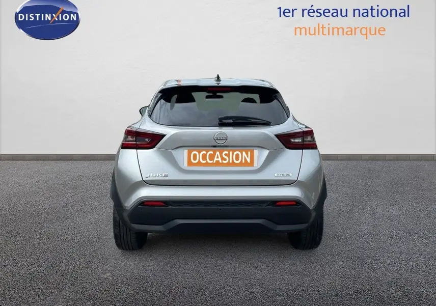 Vue arrière d'un Nissan Juke Hybrid 143ch gris perle métal, avec logo et feux arrière visibles.