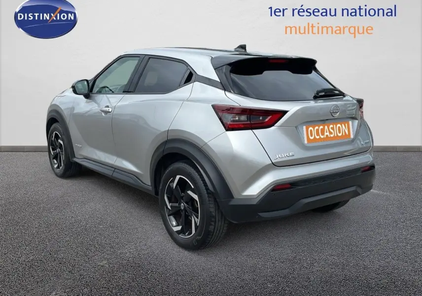 Vue 3/4 arrière droite d'un Nissan Juke hybride gris perle métal avec jantes noires et toit noir.