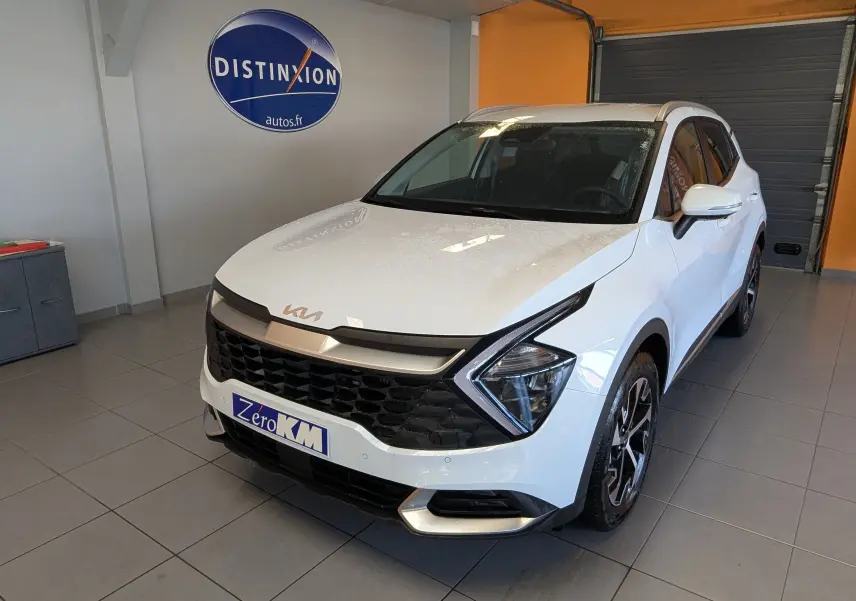 KIA SPORTAGE blanc vue 3/4 avant droit en intérieur, avec calandre noire et jantes alliage bicolores.