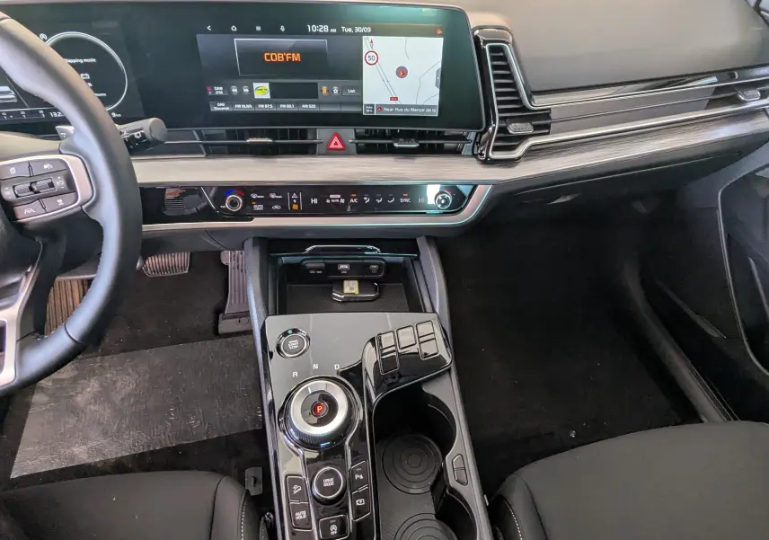 Intérieur du Kia Sportage 2025 vue du poste de conduite, avec écran tactile 12,3’’ et console centrale noire brillante.