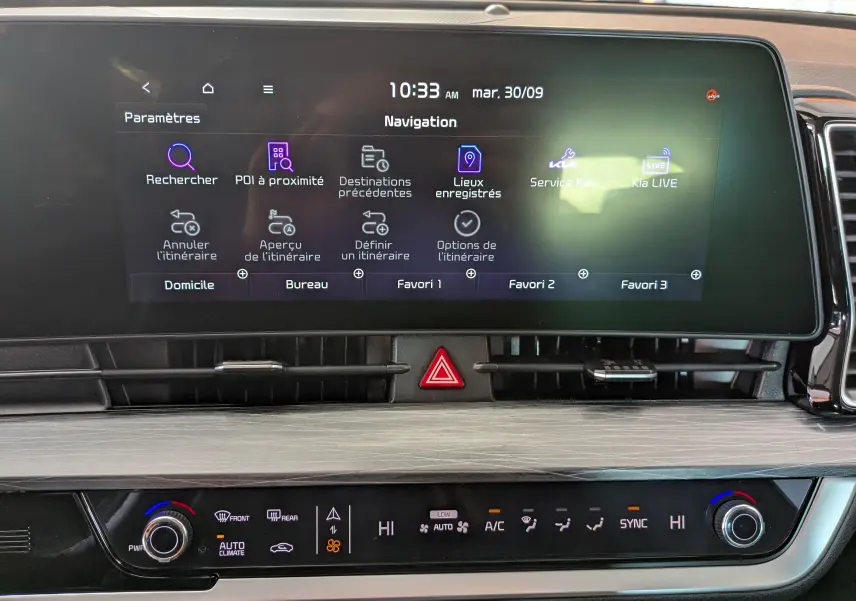 Écran tactile de navigation 12,3’’ du Kia Sportage blanc MY25 avec commandes climatisation et alertes visibles.